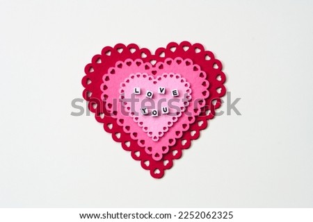 Small Letters spelling out Love You on pink and red hearts on white background, valentines concept, anniversary, holidays, relationships, love