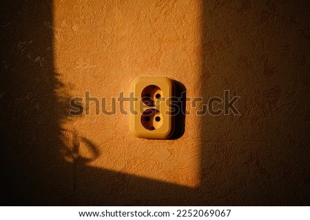Socket on the yellow wall. Power supply. Wallpaper on the wall. Royalty-Free Stock Photo #2252069067