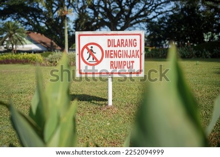 Sign of no stepping on the grass written in Indonesian language