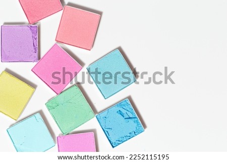 Vivid colored eye shadow makeup palette, pink, violet, blue, yellow colors on white background. Woman cosmetic and beauty product, glitter eye shadow, aesthetic texture, pastel color photo, top view