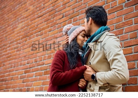Affectionate couple in love enjoying in tender moments while spending time together. Man is kissing woman in forehead.