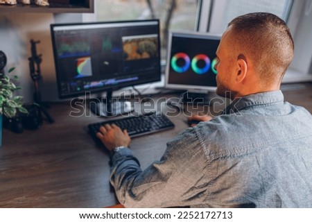 Man editing video on computer display while creating content during remote work in home studio 
