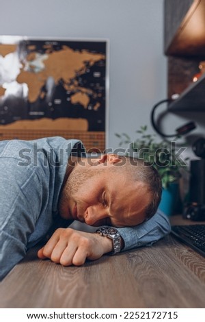 Tired male freelancer sleeping on table after hard working day in home studio  