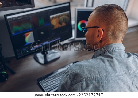 Video editor using professional software on computer screens during post production process in home studio 