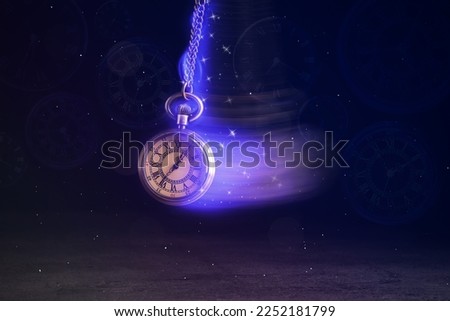 Hypnosis session. Vintage pocket watch with chain swinging over surface on dark background among faded clock faces, magic motion effect Royalty-Free Stock Photo #2252181799