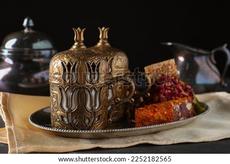 Tea and Turkish delight served in vintage tea set on black table, closeup