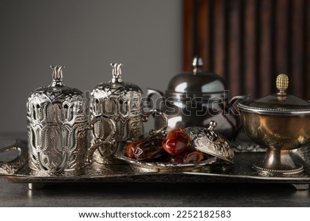 Tea and date fruits served in vintage tea set on grey textured table