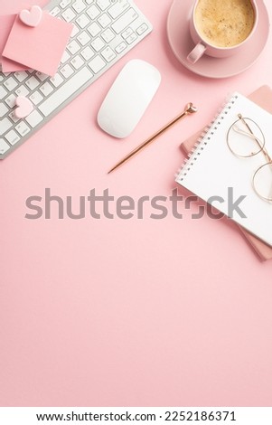 Valentine's Day concept. Top view vertical photo of keyboard computer mouse stylish pen notepads and cup of coffee on saucer on isolated pastel pink background with copyspace