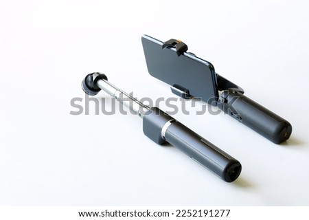 Modern mobile phone with a gimbal and a telescopic selfie stick on a white background. Close-up