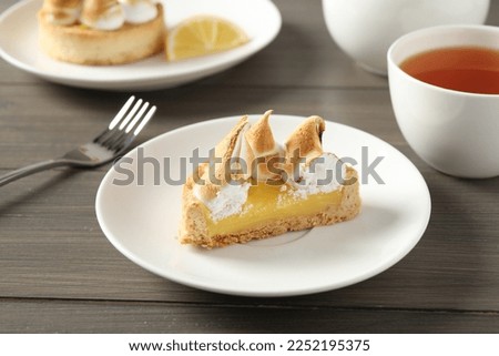 Piece of delicious lemon meringue pie on wooden table
