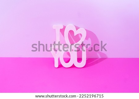 I love you white letters and a white heart on pink and magenta background. Creative concept for Valentine card or banner. Design for engagement or wedding party invitation. No people