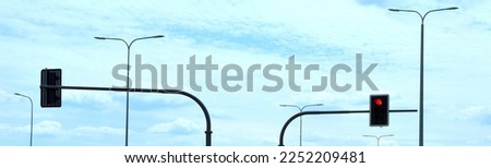 Traffic lights with red light against a bright blue sky with lanterns