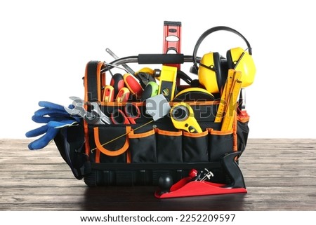 Bag with different tools on wooden table against white background Royalty-Free Stock Photo #2252209597