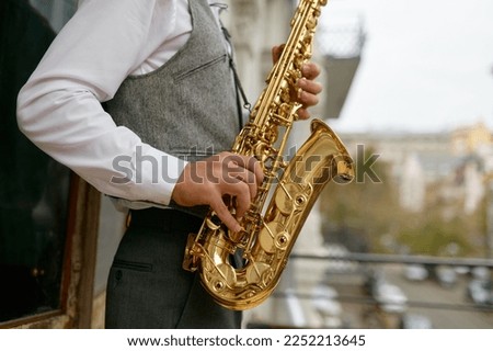 Saxophonist playing music outdoors, closeup saxophone in musician hand Royalty-Free Stock Photo #2252213645