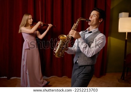 Sax man and woman fiddler duet playing classical melody Royalty-Free Stock Photo #2252213703