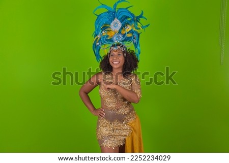 Brazilian afro woman posing in samba costume over green background with free space. Brazilian dressed Samba costume pointing