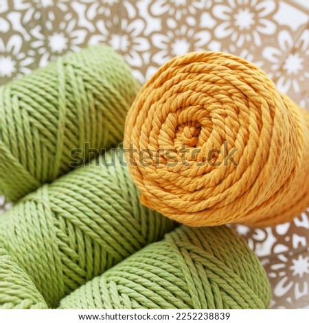 Handmade macrame braiding and cotton threads in basket on white background. 100% Cotton cord and rope against wire basket. Good image for macrame and handicrafts banners and advertisement.  Close up.