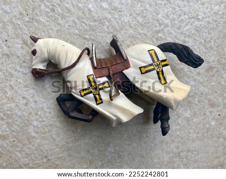 Knight Templar Horse toy black with  white blanket and  brown paddle against white tile stone background