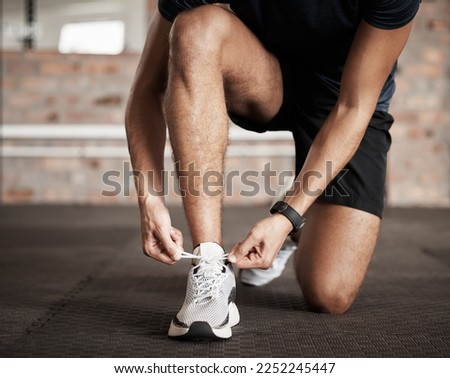 Fitness, man and tying shoe lace getting ready for running exercise, workout or training at gym. Sporty male, person or guy shoes in preparation for sport run, cardio or warm up on floor at gymnasium Royalty-Free Stock Photo #2252245447