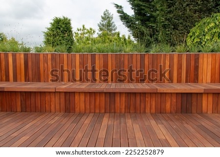 Wood fence cladding and decking, garden greenery on the background Royalty-Free Stock Photo #2252252879