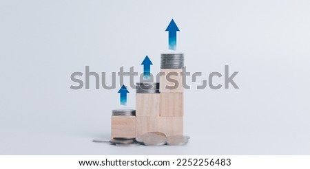 Focus on pile of US dollars on wooden table with arrow pointing up Finance and mortgage, interest rates, wooden blocks with icons and arrows pointing up that the economy is improving