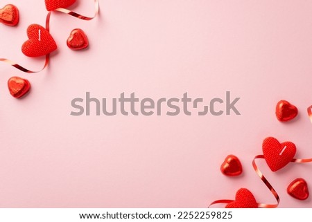 St Valentine's Day concept. Top view photo of red heart shaped candles chocolate candies serpentine and confetti on isolated pastel pink background with copyspace