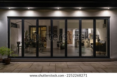 Stylish, bifold doors at night with downlighters revealing interior of a designer, luxury, lifestyle, kitchen diner room. Royalty-Free Stock Photo #2252268271