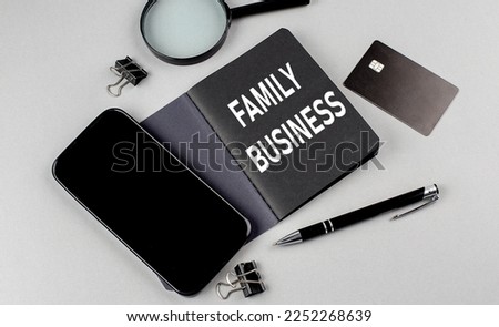 FAMILY BUSINESS text written on a black notebook with smartphone, magnifier and credit card