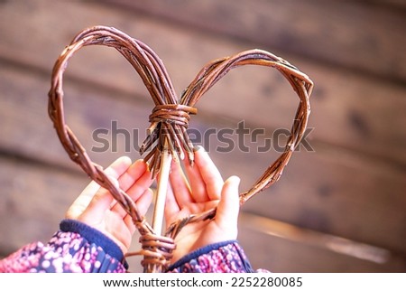 Brown wooden heart in child hands on the brown vintage wooden background. Copy space.