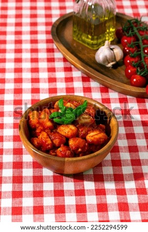 gnocchi with tomatoes and basil in a wooden bowl on a red checkered tablecloth