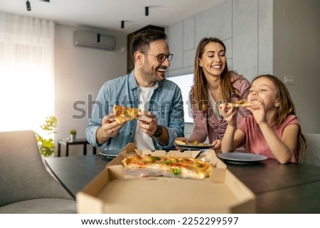 Happy family enjoying in weekend together.Happy family concept.They are eating pizza for lunch. Royalty-Free Stock Photo #2252299597