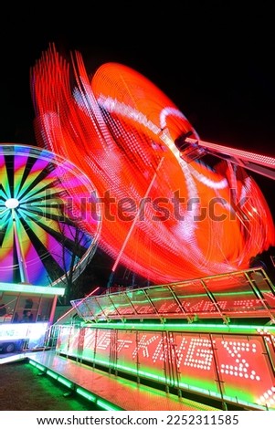Blurred rotating ferris wheel or twister with people silhouettes in amusement park in Prague in the night