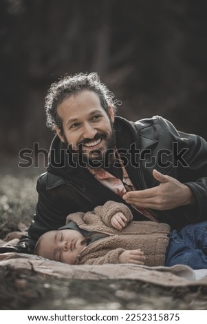 New born family photo shoot in the fall by the woods with father showing off son