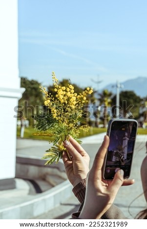 Woman taking a picture of a yellow flower 