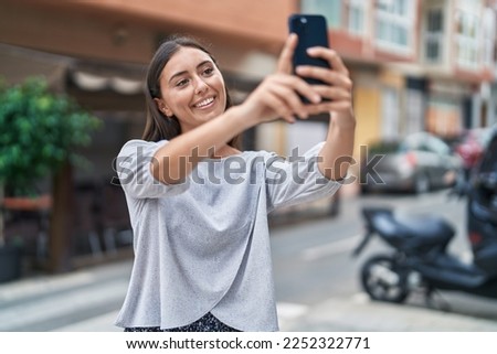 Young beautiful hispanic woman smiling confident making selfie by the smartphone at street
