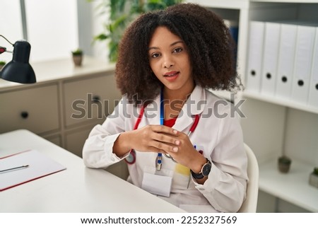 Young african american woman wearing doctor uniform speaking at clinic