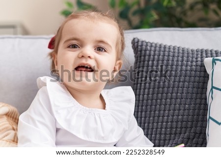 Adorable blonde toddler smiling confident sitting on sofa at home