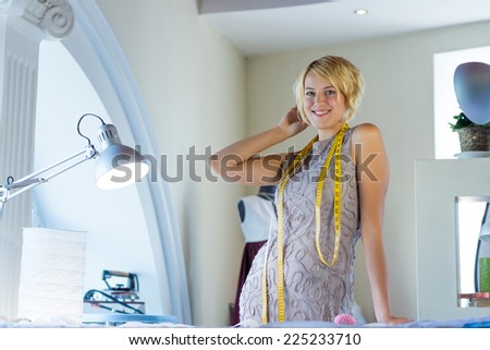 Young attractive needlewoman in studio standing at workplace