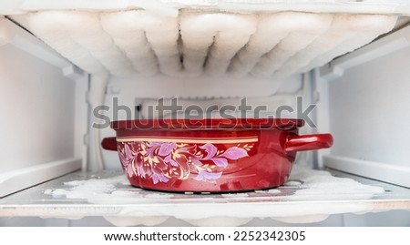 Defrost Freezer.  container covered with melting ice, water in the refrigerator. Royalty-Free Stock Photo #2252342305