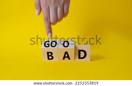 Good vs Bad symbol. Businessman Hand points at wooden cubes with words Bad and Good. Beautiful yellow background. Business and Good vs Bad concept. Copy space