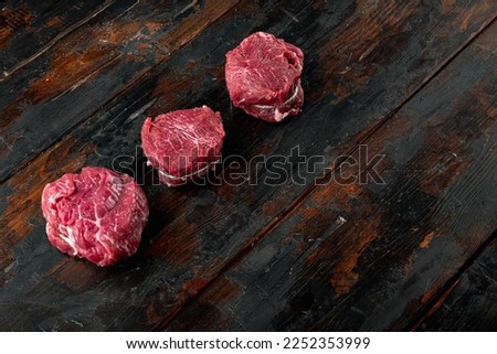 Fresh raw fillet minion steaks marbled beef with rosemary and garlic set, on old dark  wooden table background, with copy space for text