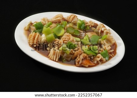 squid (Calamari) with green Pepper, Is a popular Indo-Chinese delicacy all over India. Battered sea food, Chinese cuisine pictures, isolated on Black background.