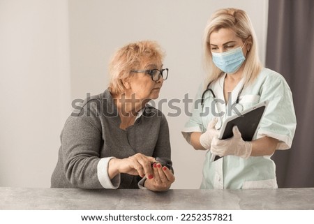 Homehealth care. Woman nurse in a medical mask help middle aged woman during during illness or pressure, female doctor measures the patient's pulse and oxygen saturation using a pulse oximeter.