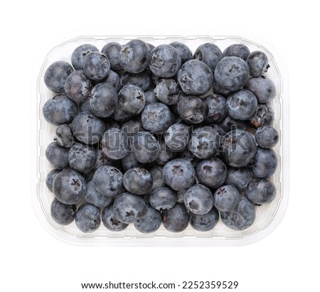Whole fresh blueberries, in a clear plastic punnet, from above. Dark blue colored, ripe, raw fruits of Vaccinium corymbosum, berries of the northern highbush blueberry. Isolated, close-up, food photo. Royalty-Free Stock Photo #2252359529