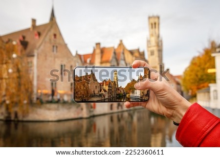 Traveling old Europe. Taking the picture of Brugge iconic view via smartphone Royalty-Free Stock Photo #2252360611
