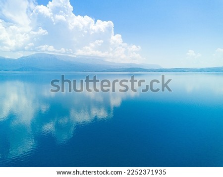 Majestic huge white thick clouds float across the clear blue daytime sky above the horizon with the shallow azure calm Adriatic Sea in the light of the bright summer sun Royalty-Free Stock Photo #2252371935
