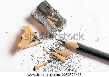 METAL PENCIL SHARPENER WITH BLACK PENCIL SHAVINGS. HORIZONTAL PHOTOGRAPHY. COLOR.  Royalty-Free Stock Photo #2252372645