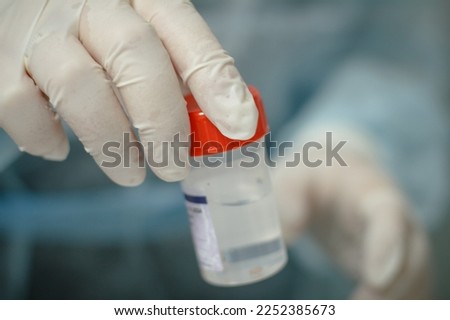 A doctor in a medical glove holds a container with a biopsy in his hand for analysis. In the hand is a jar with farmalin and a piece of biopsy to be sent to the laboratory. Royalty-Free Stock Photo #2252385673