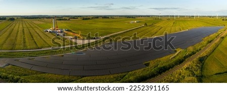 Panorama aerial view of solar energy panel photovoltaic cell and construction of wind turbine farm power generator in nature landscape for production of renewable green energy.