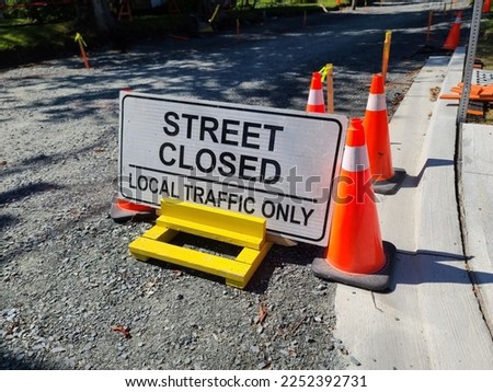 A local traffic only sign with orange cones around it on a gravel street.